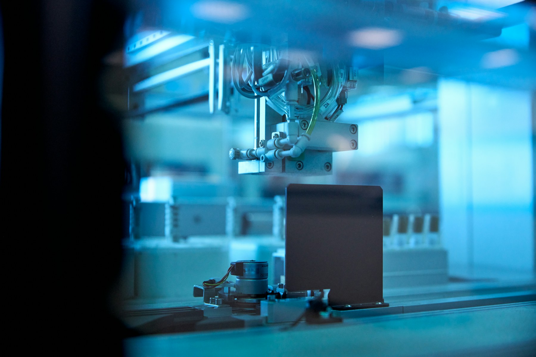 A robotic sample-processing mechanism in a blue-lit laboratory enclosure